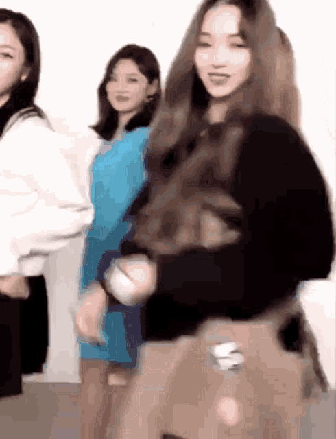 a group of girls are standing next to each other and one of them is wearing a black sweater