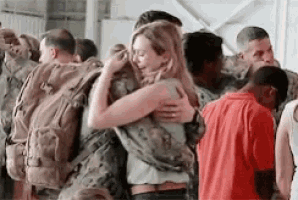 a woman hugging a soldier in a crowd of people .