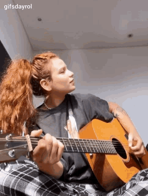 a woman is playing an acoustic guitar in a room .