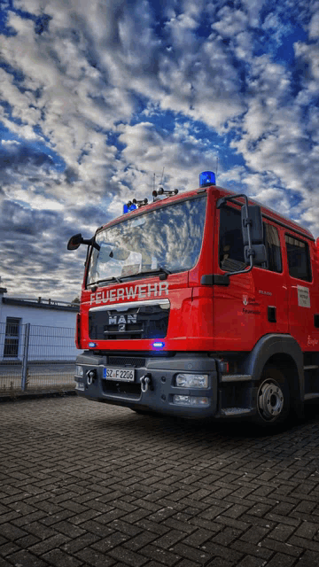 a red feuerwehr truck is parked on a brick pavement