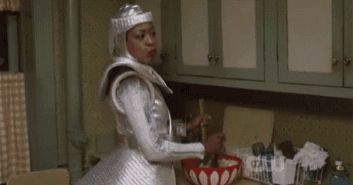 a woman in a silver costume is standing in a kitchen with a bowl of food .