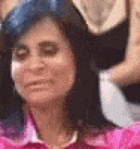 a woman in a pink shirt is making a funny face in a crowd of people .