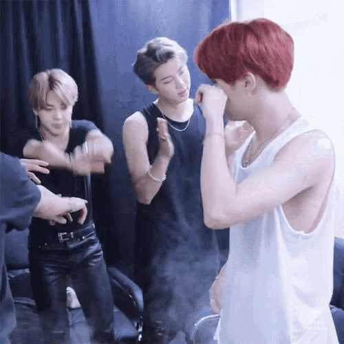 a group of young men are standing in a room and one has red hair