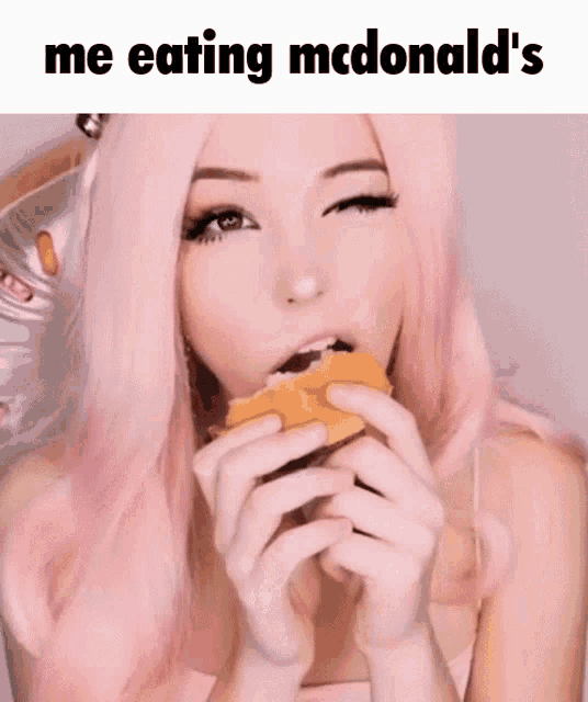 a girl with pink hair eating a mcdonald 's hamburger