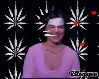 a woman is smiling and smoking a cigarette with marijuana leaves behind her