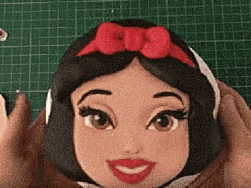 a close up of a doll 's face with a red bow on her head .