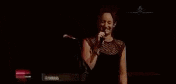 a woman is singing into a microphone on stage .