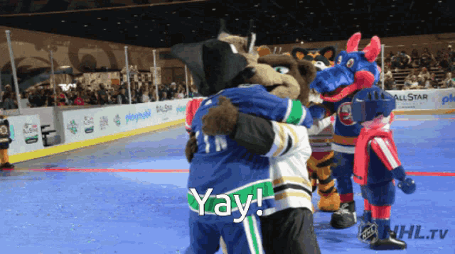 a group of mascots are hugging and the word yay is on the bottom right
