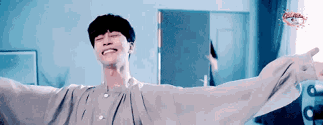 a man with his arms outstretched is smiling in a room with a blue background