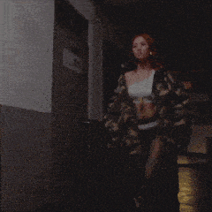 a woman with red hair is standing in a dark hallway with her hands in her pockets