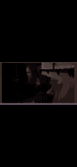 a woman is sitting in a dark room with a purple border