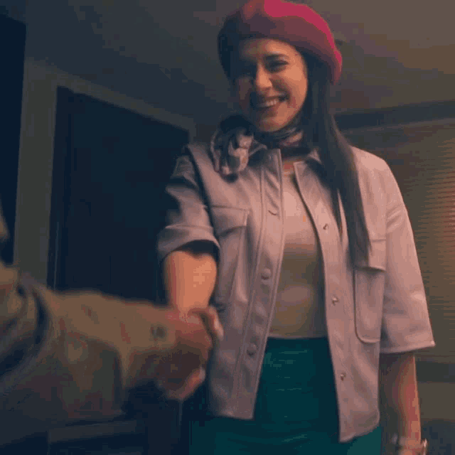 a woman wearing a pink beret shakes hands with a man in a suit