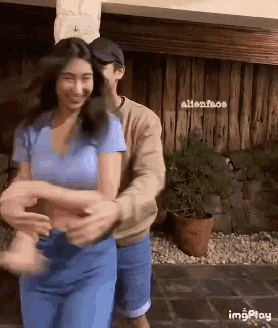 a man is hugging a woman in front of a wooden building .