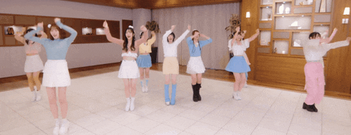 a group of girls are dancing in a room with their hands in the air