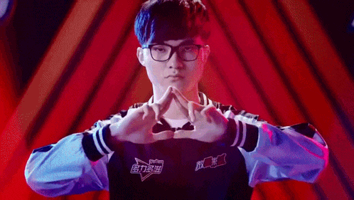 a man wearing glasses is making a heart shape with his hands .
