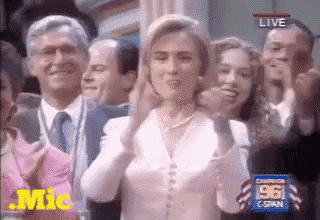 a woman in a white shirt is standing in front of a crowd of people applauding ..