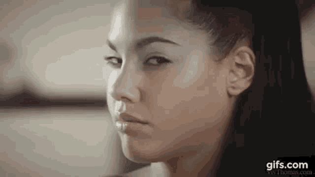 a close up of a woman 's face with her eyes closed and her hair in a ponytail .