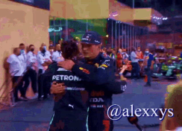 two men hugging with one wearing a petron shirt