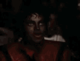 a close up of a man wearing a red jacket and black makeup .