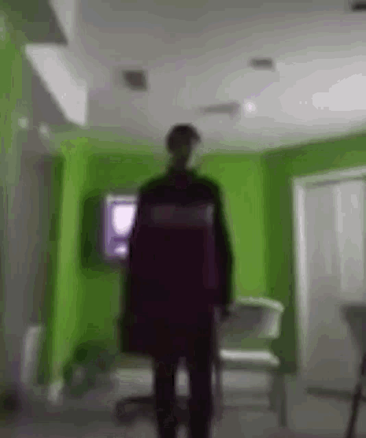 a blurry picture of a man standing in a living room with green walls .