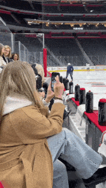 a woman taking a picture of a hockey game with her phone