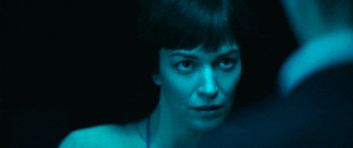 a woman is looking at herself in a mirror in a blue light