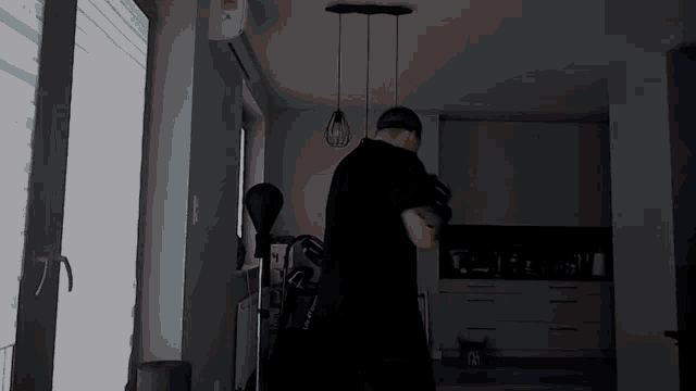 a man in a black shirt is standing in a dark room holding a dumbbell