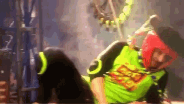 a person wearing a green shirt with a superman logo on it is laying on the floor .