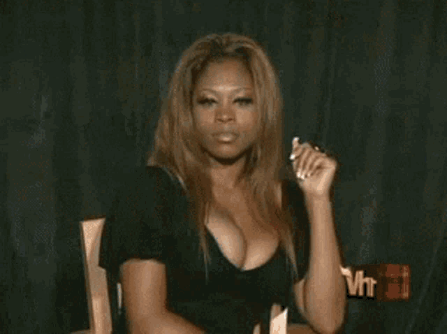 a woman with a very large breast is sitting at a table in front of a mtv logo .
