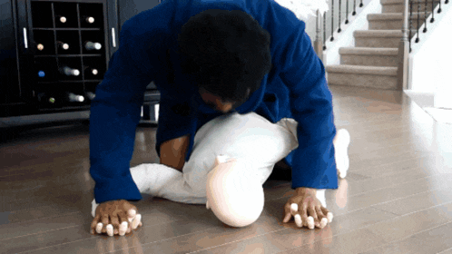 a man in a blue jacket is doing push ups on a baby