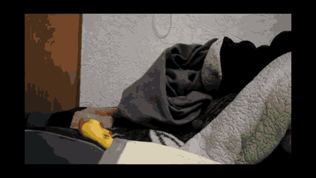 a yellow rubber duck is laying on a bed with a blanket