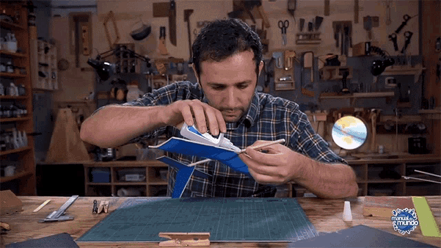 a man in a plaid shirt is gluing a piece of paper in front of a sign that says oficina del mundo