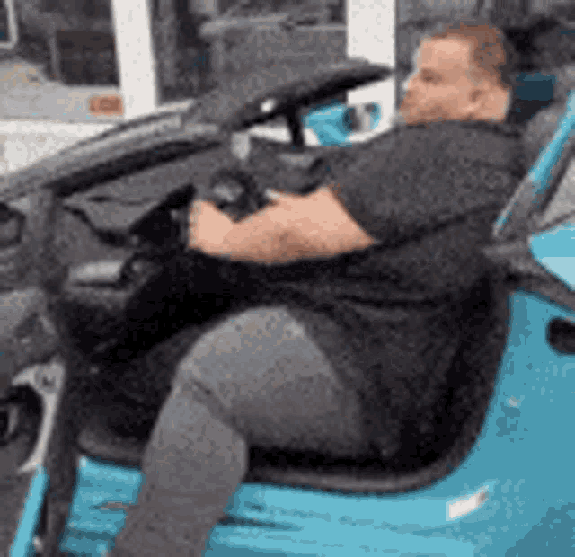 a man is sitting in a blue golf cart with his legs crossed .