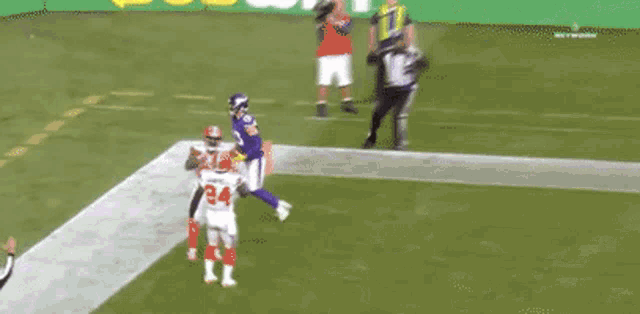 a football player in a purple uniform is running on a field with a ball .