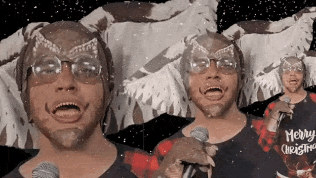 a man singing into a microphone wearing a merry christmas shirt