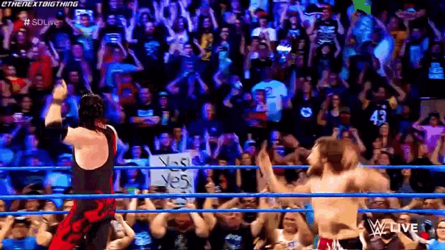 a man in a wrestling ring holds up a sign that says yes