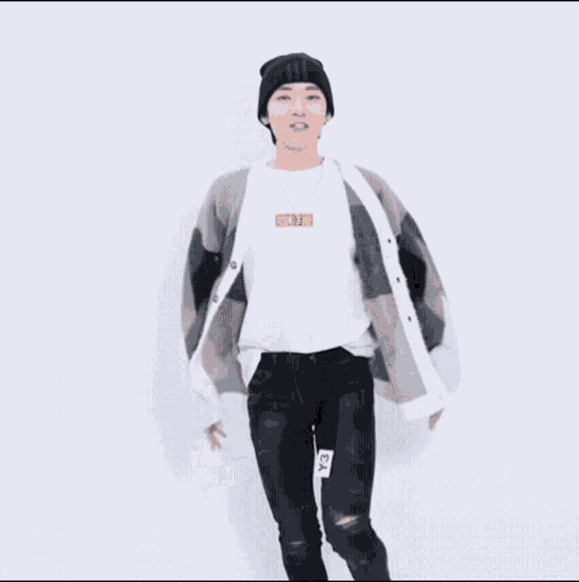 a young man wearing a hat and a cardigan is dancing .