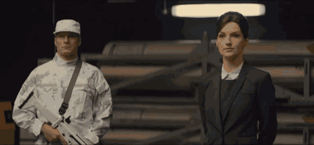 a woman in a suit stands next to a man in a military uniform
