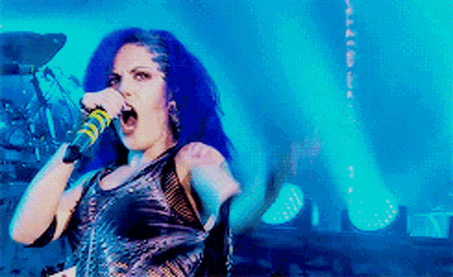 a woman with blue hair is singing into a yellow and black microphone