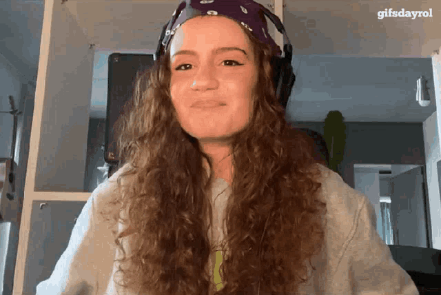 a woman with curly hair wearing headphones and a purple bandana with gifsdayrol written on the bottom
