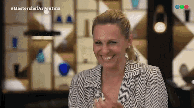 a woman in a black and white striped jacket is smiling and clapping