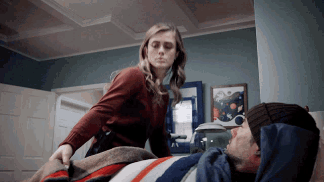 a woman standing next to a man in a bed