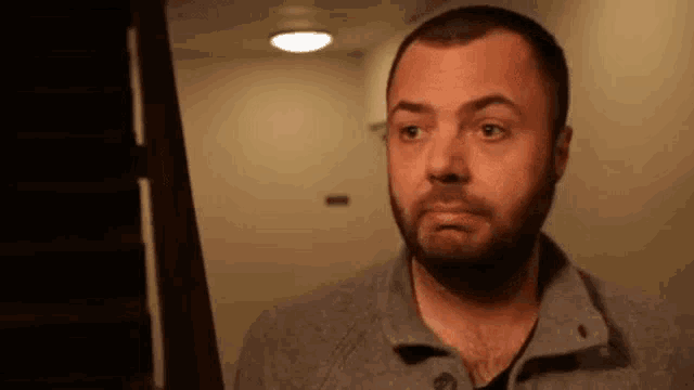 a man with a beard is making a funny face while looking at the camera .
