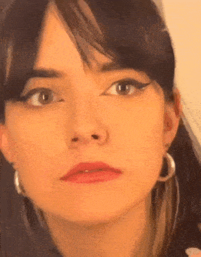 a close up of a woman 's face wearing hoop earrings and making a face .