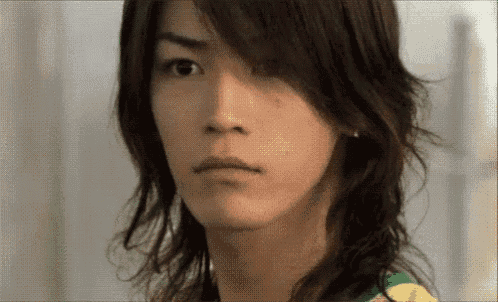 a close up of a young man 's face with long hair .