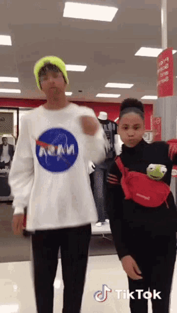 a man wearing a nasa shirt is standing next to a girl