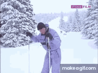 a man in a ski suit is standing in the snow with a pink film logo above him