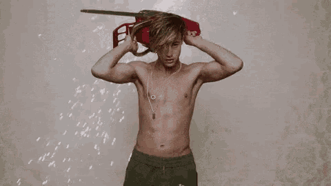a shirtless young man is holding a red sword over his head .