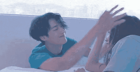 a man and a woman are playing with each other on a bed . the man is holding the woman 's head .
