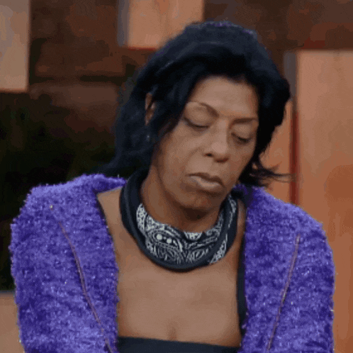 a woman wearing a purple sweater and a bandana looks down